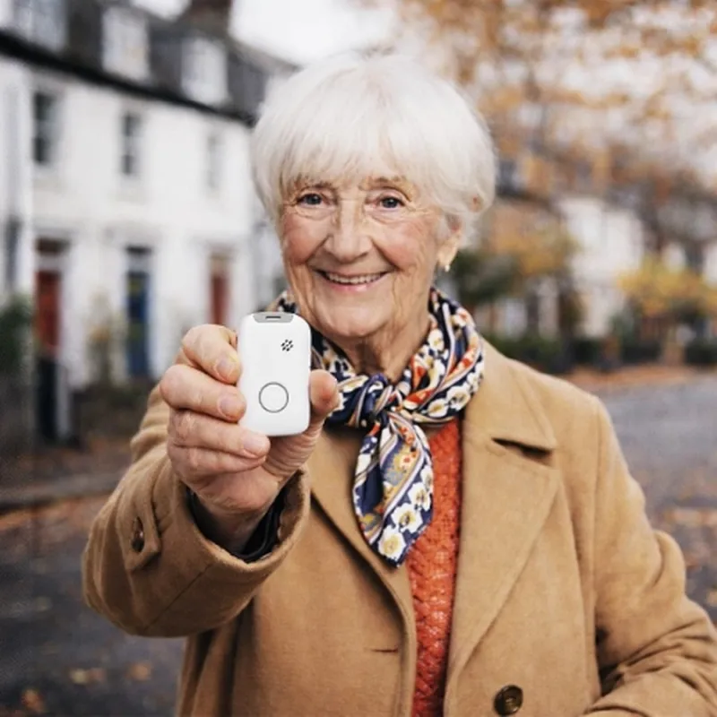 Seniorin hält ihren mobilen Hausnotruf-Knopf in die Kamera